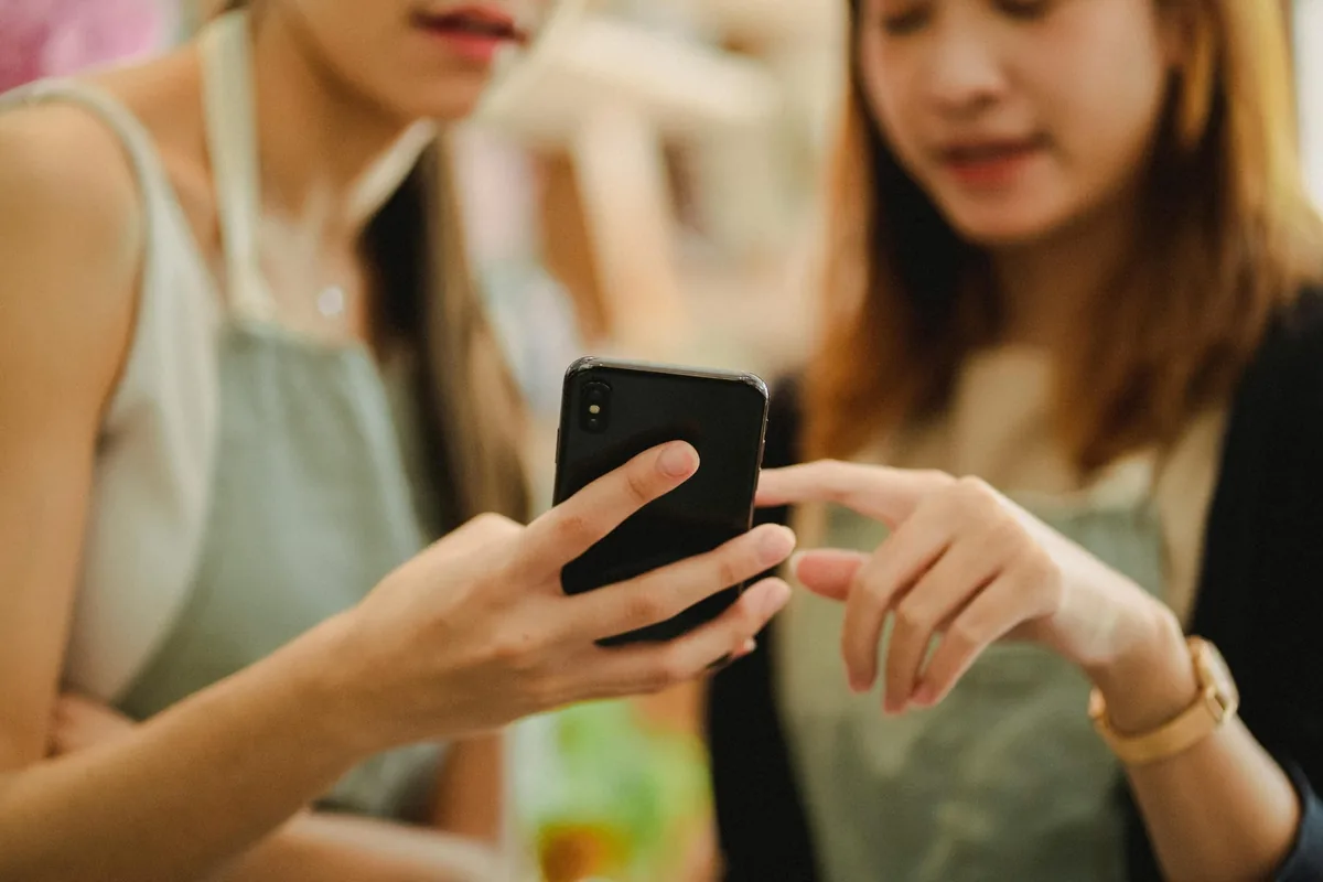 Duena de salon de belleza sonriendo con su celular — tranquila porque Hoolik maneja sus citas